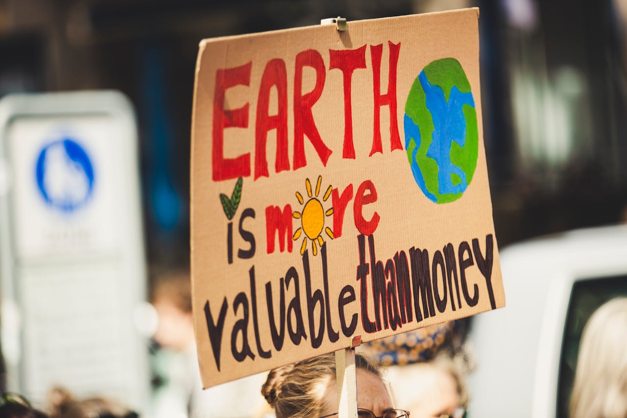 about-us Sign reading 'Earth is more valuable than money' at a climate protest outdoors.